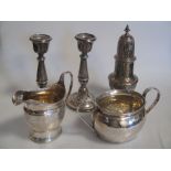 A silver sugar caster, cream jug, sugar bowl and a pair of loaded silver candlesticks 13.5ozt