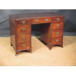 A George III style mahogany kneehole desk with canted reeded sides with brass handles on swept