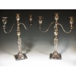 A pair of silver plated candlesticks in the neo-classical manner; two branch and three light, with