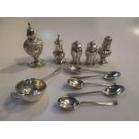 Five small silver peppers, five coffee spoons, and a tea strainer