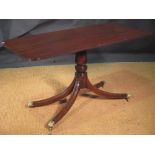 A George III style narrow mahogany pedestal table on splayed legs with brass lion paw cast feet on