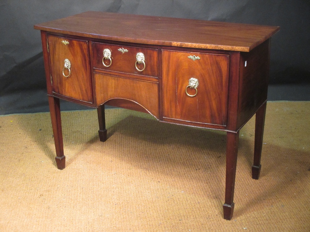 A small Regency style mahogany bow front sideboard with brass lion mask and ring handles, on