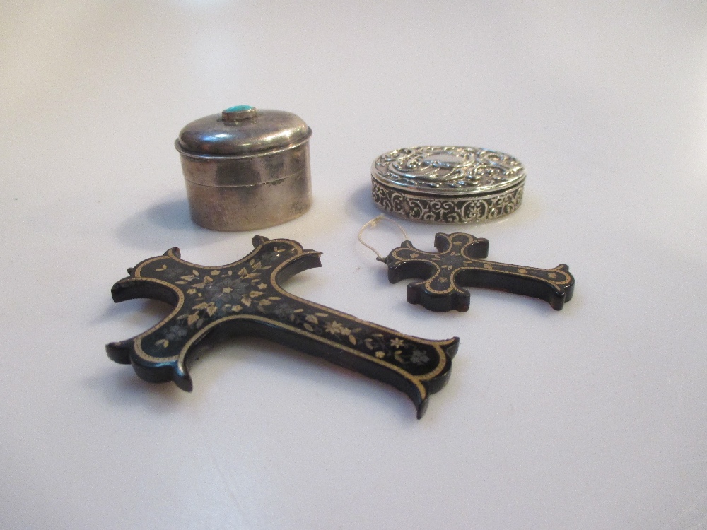 Two decorated crucifixes with inlaid detail, a silver pill box and another with turquoise finial