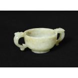 A small jade twin handled cup, 19th century, of compressed globular form and raised on a low foot,