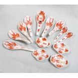 A 19th century set of iron red spoons and four small saucers, comprising nine spoons of different