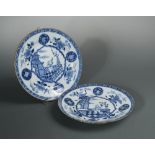 A pair of Kangxi blue and white dishes, painted with a child on the centre in a veranda within