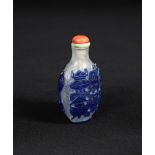 A 19th century glass overlay snuff bottle, carved with blue overlay 'antiques' on both sides, 7cm