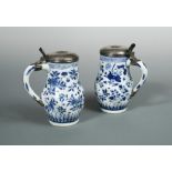A pair of Transitional blue and white lidded tankards, the spiral lobed sides painted with flowers