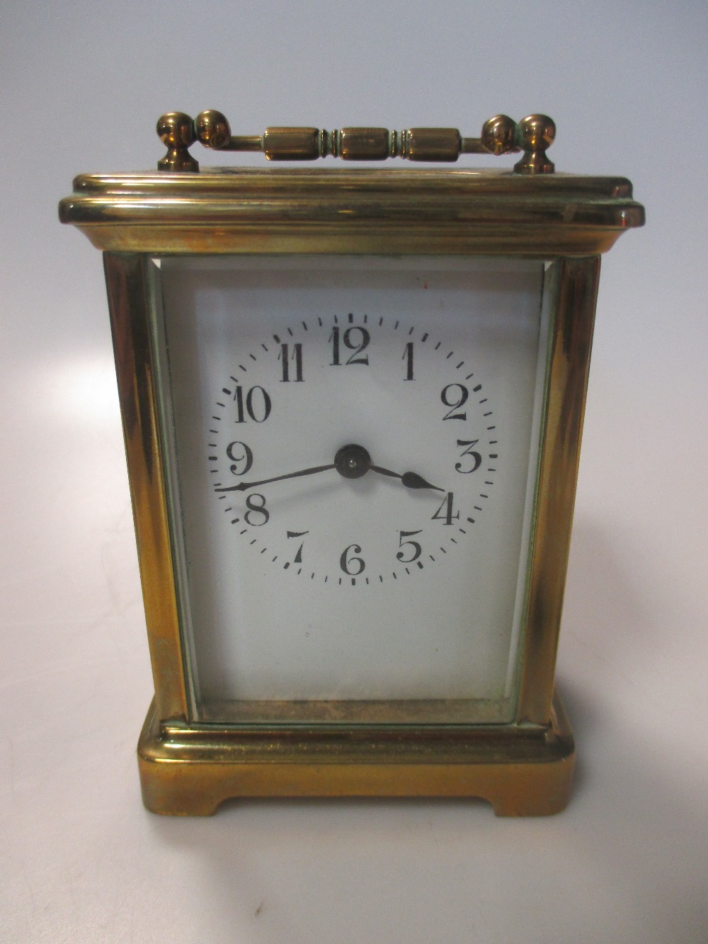 A brass carriage timepiece, with Arabic numerals, in a leather travel case