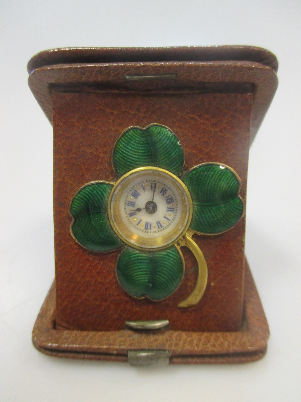 A leather cased travelling timepiece with four leaf clover enamel mount