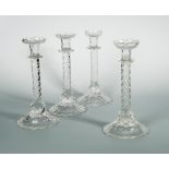 A matched set of four cut glass candlesticks, the stylised foliate sconces on knopped prismatic