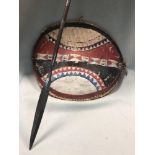 A tribal shield and a spear, possibly Masai, the spear shaft wrapped in tri-colour metal, the oval