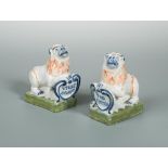 A pair of faience pottery lions, each resting their paw on a scrolled shield, one inscribed 'Vivat