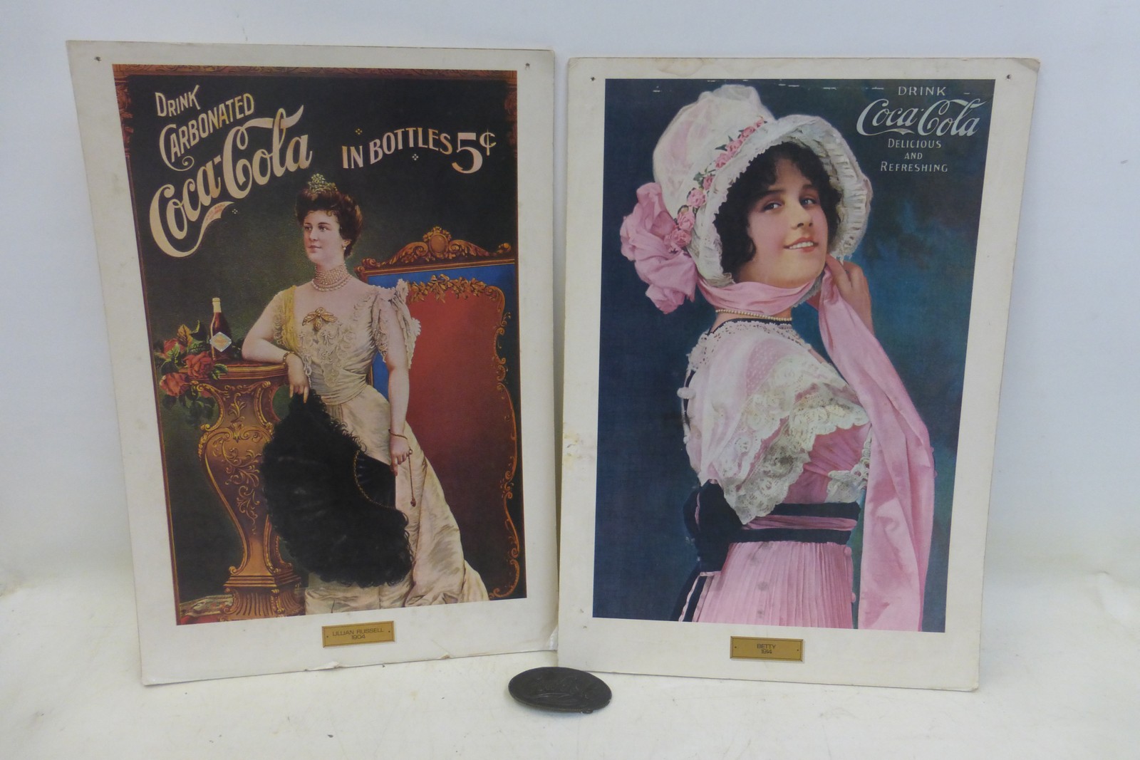 A pair of older reproduction Coca Cola showcards, probably 1970s/1980s and a Coca Cola oval belt