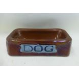 An unusual brown glazed pottery dog bowl, with an Art Nouveau design 'Dog' motif, by repute Royal