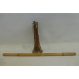 A copper and brass military bugle with applied badge and a bamboo swagger stick.