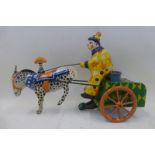 A clockwork tinplate model of a clown on a horse drawn cart, age and origin unknown.