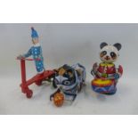 A Chinese clockwork tinplate drumming panda, a Korean clockwork tinplate recumbant cat and a clown