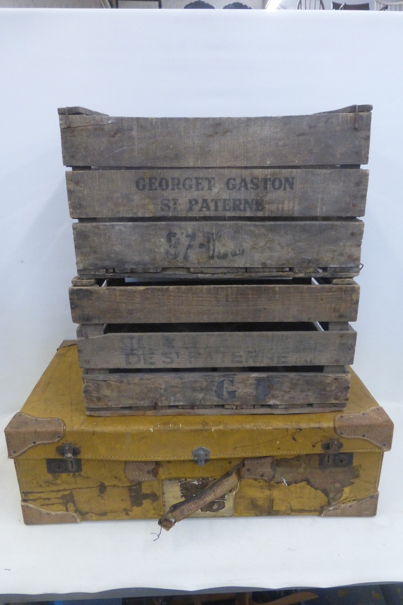 A large mustard coloured travelling trunk and two wooden crates.