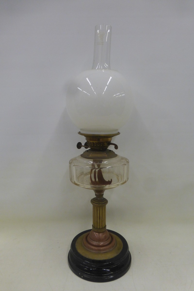 A late Victorian part brass oil lamp with a clear glass reservoir, opaque glass shade and finial.