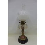 A late Victorian part brass oil lamp with a clear glass reservoir, opaque glass shade and finial.