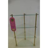 A brass and glass triangular four tier cosmetic/perfume stand with paper tag.