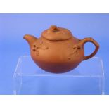 An antique oriental red pottery Yixing Teapot, the squat ovoid body decorated in relief with