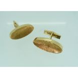 A pair of 14k yellow gold Cufflinks, of long oval form with concave textured centres, hinged bar