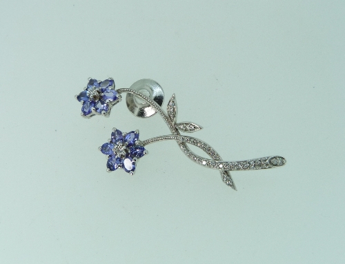 A 14k white gold Lapel Pin / Brooch, formed of two intertwined flowers, the stems and leaves set