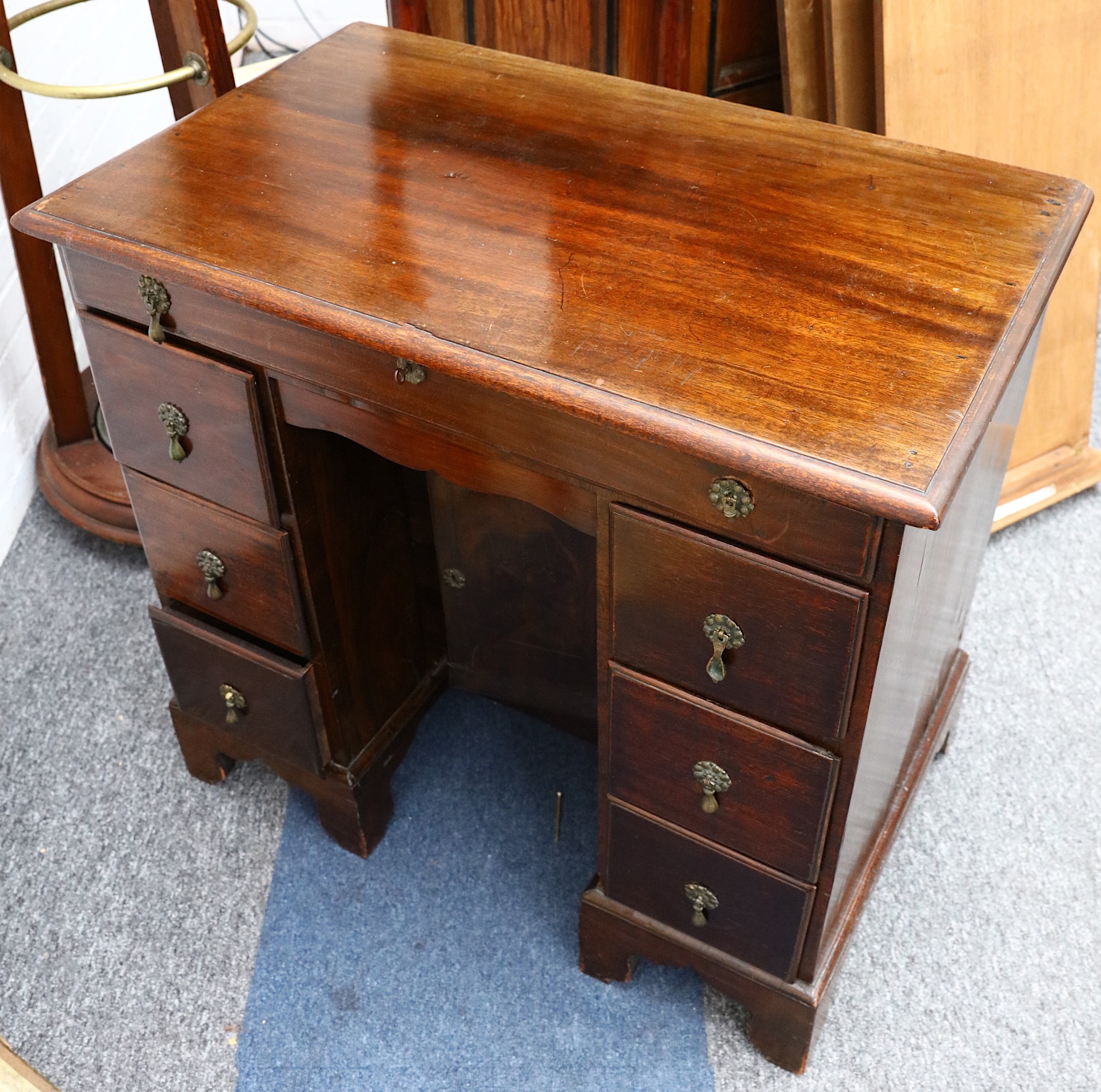 A George II style mahogany kneehole desk, early 20th Century, fitted with seven drawers around a