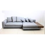 A large Minotti sofa, upholstered in blue grey, the end with brown leather table on metal feet,