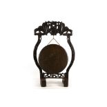 A Chinese floor-standing gong, the carved hardwood frame supporting a bronze gong, 85cm high, the