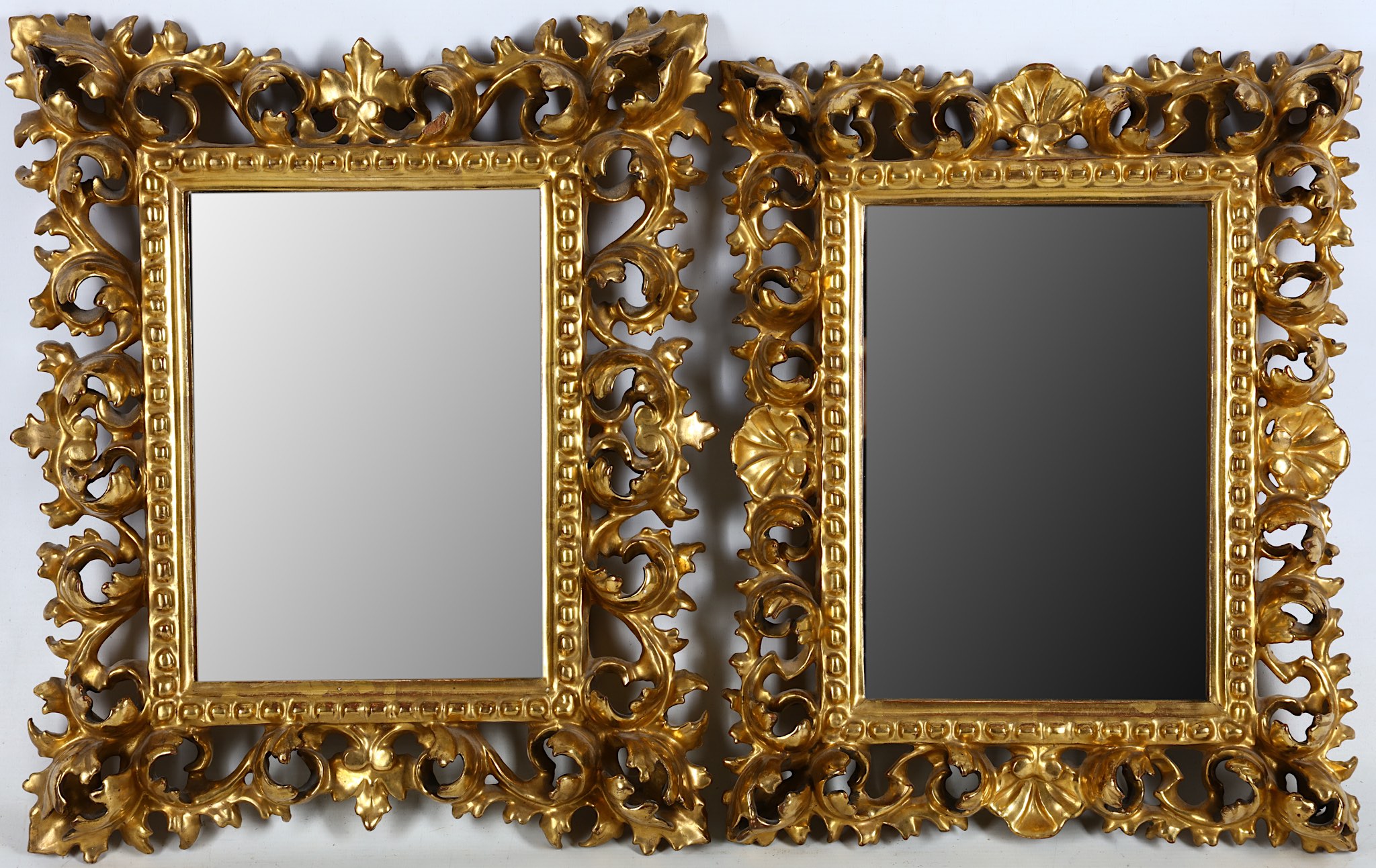 A near pair of Florentine carved giltwood wall mirrors, late 19th or early 20th century, the