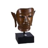 A Thai bronze Buddha face, Thailand, 20th century, mounted onto wooden block base, 56cm high