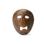 A COCONUT MASK, SOUTH PACIFIC Circa 19th Century, This miniature mask has a tragic expression almost