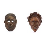 TWO WOOD MASKS  The first of rounded shape with large hollow eyes and an off-centre mouth with bared