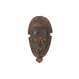 A GURO MASK, IVORY COAST With a long oval face with downward sloping slit eyes, arched brows that