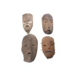 FOUR AFRICAN WOOD MASKS All of highly stylised form, with simple carved faces, possibly from Ivory