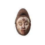 A BAULE MASK, IVORY COAST With a tall headdress decorated with linear incisions, the face of the