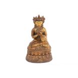 A Tibetan gilt metal figure of a seated Buddha