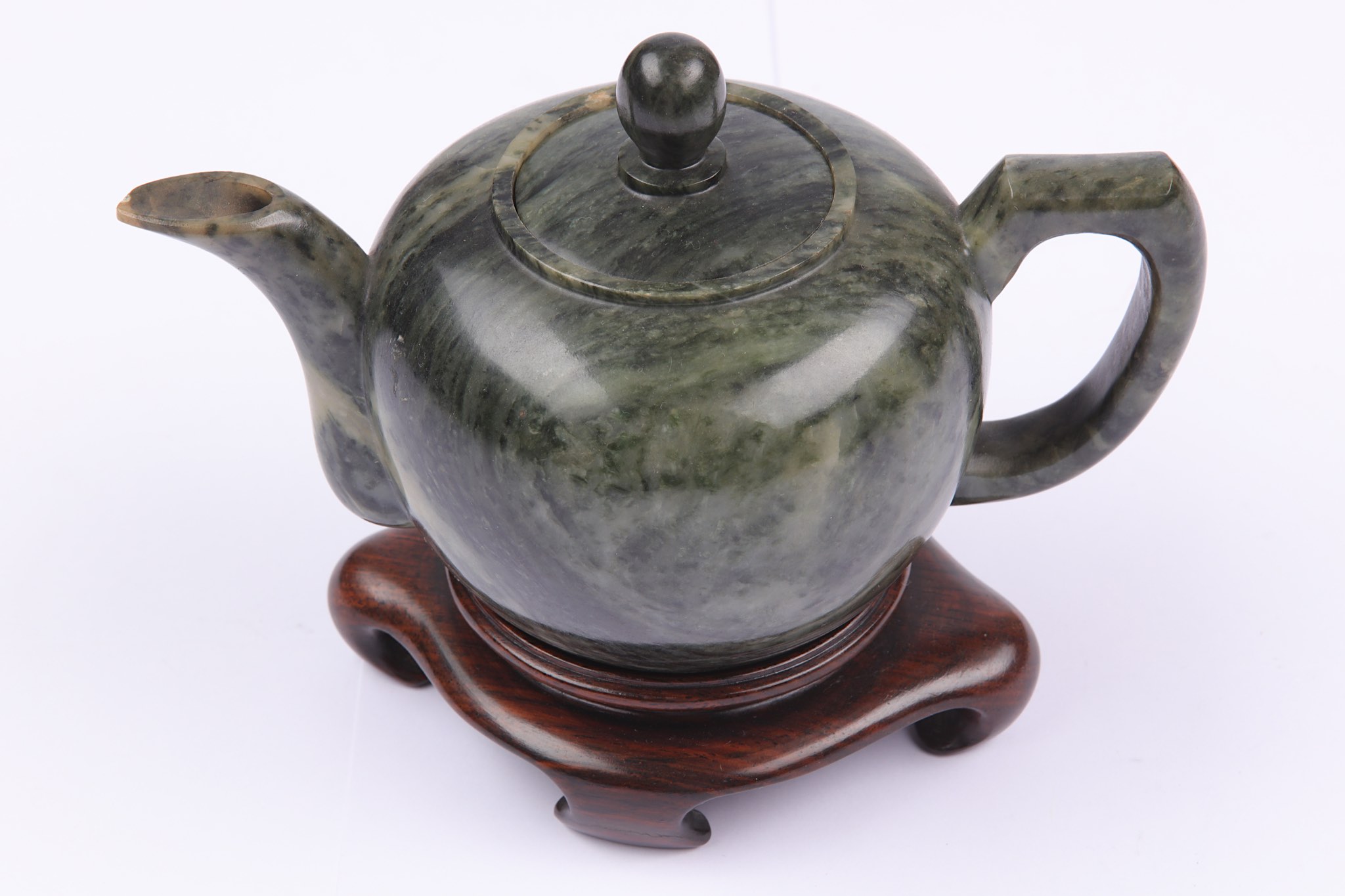 A Chinese green hardstone teapot and cover, 20th century, of compressed globular form, on a hardwood