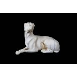 A LATE 18TH / EARLY 19TH CENTURY CARVED IVORY MODEL OF A HOUND the reclining beast raised on a black