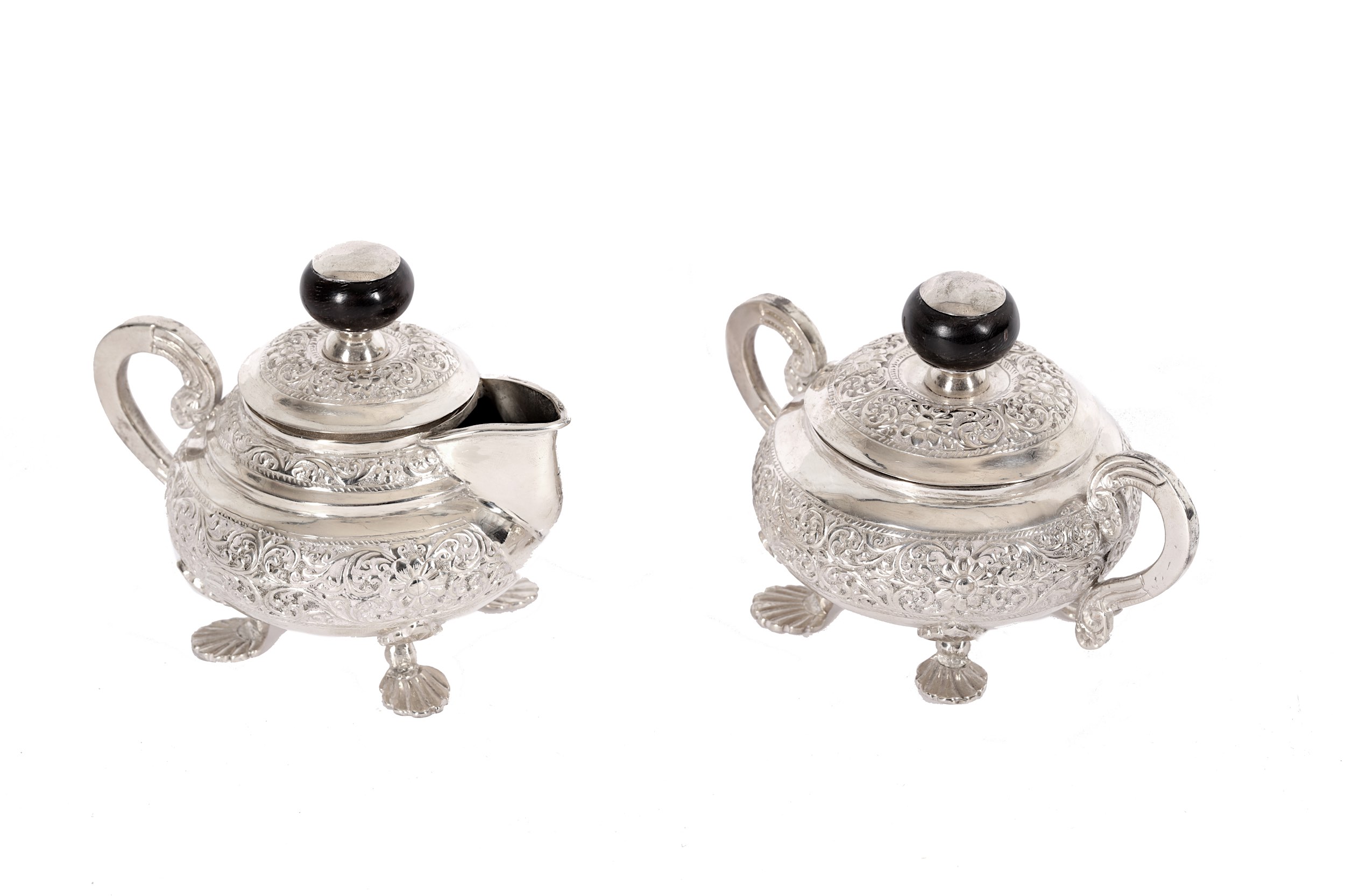 An Indian embossed white metal three-piece tea set, with ebonised mounts (3) - Image 2 of 2