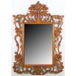 A continental fruitwood wall mirror, late 19th or early 20th Century, the pierced and carved frame
