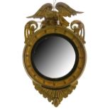 A Regency giltwood convex mirror, with moulded cavetto frame, surmounted by carved eagle, flanked by