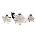 An Indian embossed white metal three-piece tea set, with ebonised mounts (3)