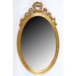 A giltwood oval framed mirror, 19th Century, with a ribboned pediment