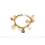 A charm bracelet, the 9 carat gold curb-link bracelet suspending several charms including a