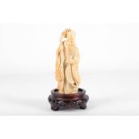 A Japanese carved ivory okimono, Meiji period, 19th Century, carved as a scholar or deity, on a