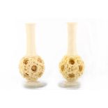 A pair of Chinese ivory puzzle ball vases, early 20th Century, both with a long slender neck